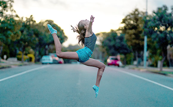 chica saltando en medio de una calle vacía