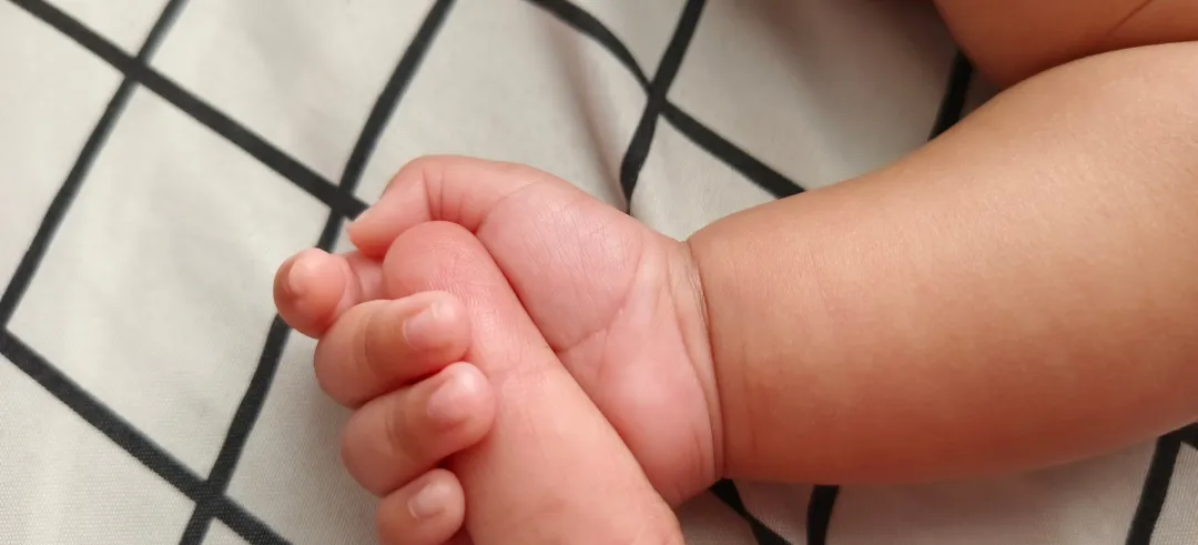 Mano de bebé agarrando el dedo de una persona adulta