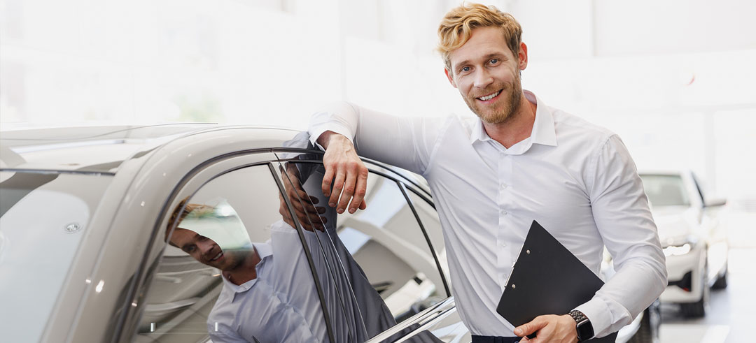 Hombre vendedor de coches mostrando un vehículo en concesionario
